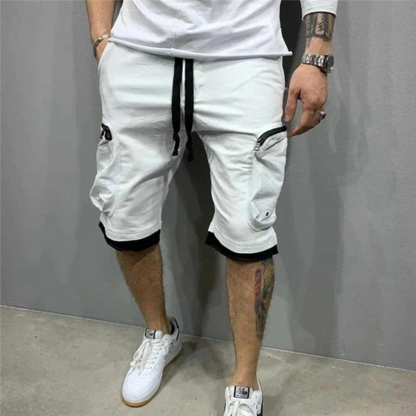 Witte cargoshorts voor heren met zwarte trekkoord, zakken met rits, casual streetwear stijl, gecombineerd met witte sneakers en een wit T-shirt.