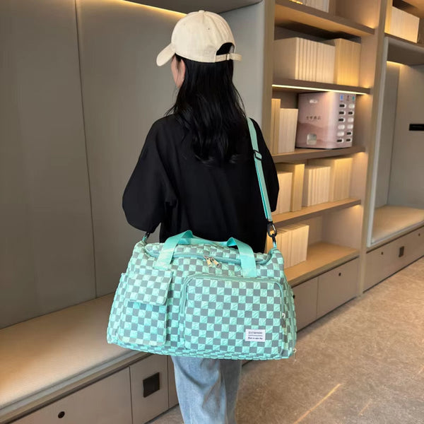 Vrouw met zwarte jas en beige pet draagt een mintgroene geruite reistas in moderne bibliotheek. Stijlvolle damestas, trendy modeaccessoire.