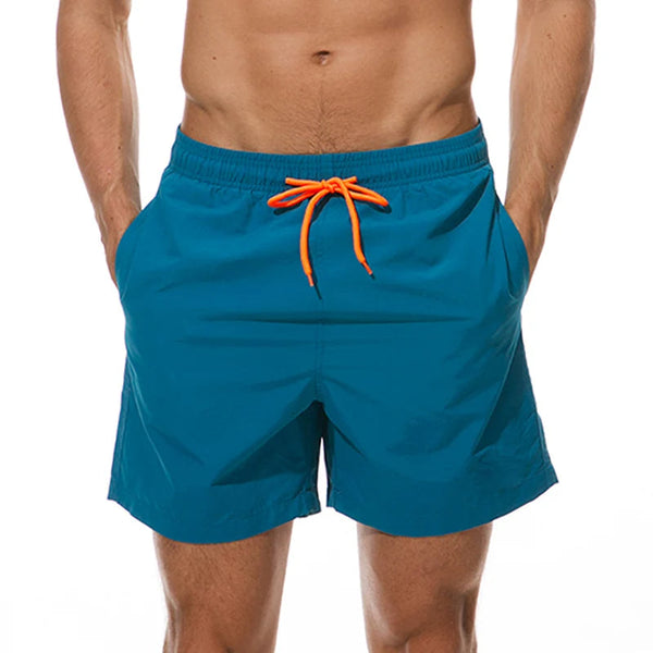 Blauwe zwembroek met oranje koord, gedragen door man. Perfect voor strand en zwembad. Comfortabele pasvorm, modieus design. Ideaal voor zomerse activiteiten.