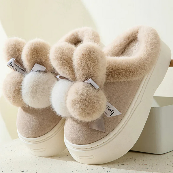 Beige pluche pantoffels met dikke zool en decoratieve pompons, ideaal voor wintercomfort. Warme dameshuisschoenen, stijlvol en knus.