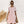 Vrouw in roze-wit gestreepte jurk met korte mouwen, zonnebril en rieten handtas. Zomermode, casual dameskleding, trendy outfit.