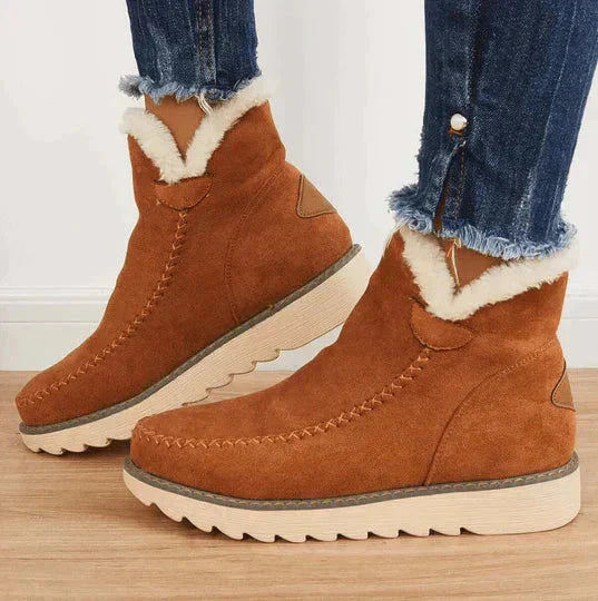 Bruine suède enkellaarsjes met witte voering, geribbelde zool en gestikte details. Perfect voor wintermode en casual outfits.