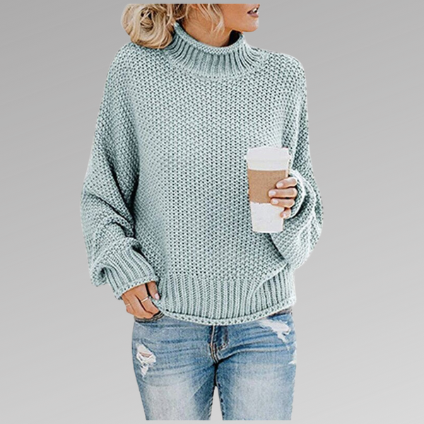 Vrouw in lichtblauwe gebreide trui met opgerolde mouwen, houdt een kartonnen koffiebeker vast. Casual mode, herfstkleding, comfortabele stijl.