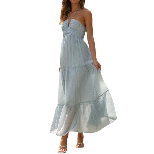 Lange lichtblauwe zomerjurk met halternek, vloeiende stof en gelaagde rok. Perfect voor strandmode en zomerse evenementen.