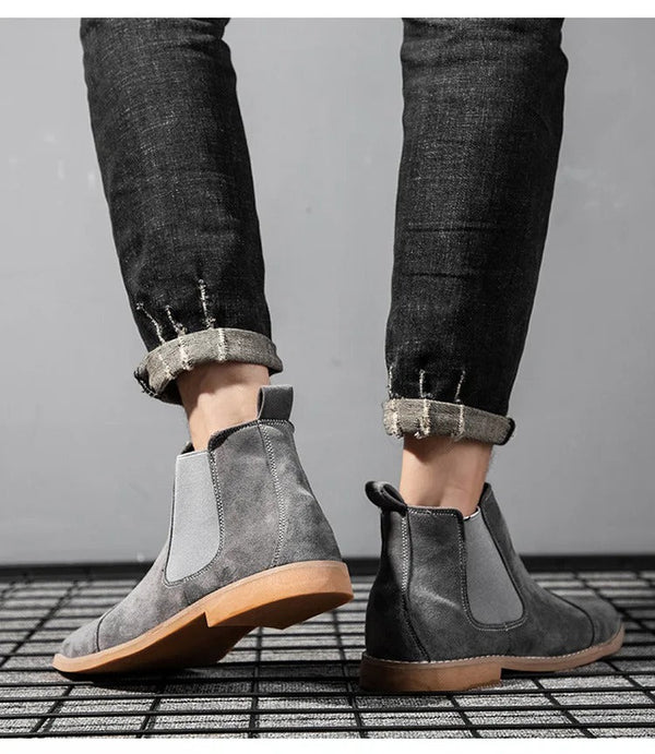 Grijze suède Chelsea boots voor heren, gedragen met opgerolde zwarte jeans. Stijlvolle herenschoenen, casual mode, comfortabele pasvorm.