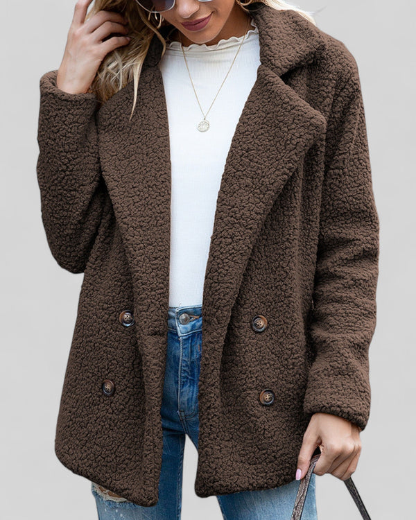 Vrouw in bruine teddyjas, witte trui en spijkerbroek. Modieuze herfstkleding, comfortabele damesjas, trendy casual outfit.
