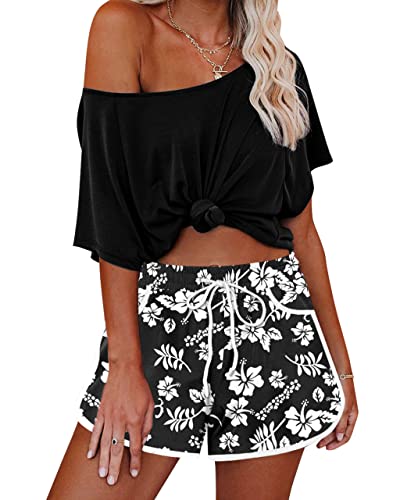 Vrouw in zwarte off-shoulder top en zwart-witte bloemenprint shorts. Zomerse casual outfit, strandkleding, modetrend 2023.