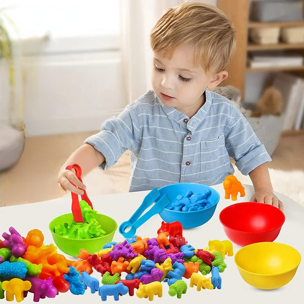 Kleuter speelt met kleurrijke plastic dierenfiguren en kommen op tafel, educatief speelgoed, motorische ontwikkeling, binnenshuis, kindervermaak.