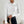 Vrouw in elegante witte, lange mouwen top met gedrapeerde halslijn, zwarte broek en beige handtas. Modieuze dameskleding, minimalistisch design.