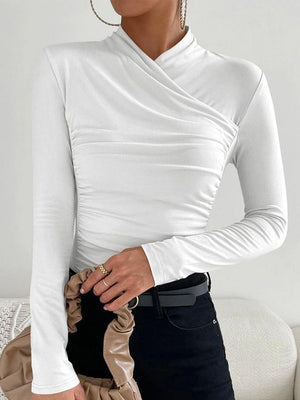 Vrouw in elegante witte, lange mouwen top met gedrapeerde halslijn, zwarte broek en beige handtas. Modieuze dameskleding, minimalistisch design.