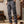 Man in casual outfit met grijze cargobroek en bruine laarzen, staand op houten vloer. Stijlvolle herenkleding, comfortabele vrijetijdskleding.