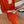 Vrouw in oranje gebreide jurk en vest leest krant, zittend op houten vloer. Stijlvolle herfstmode, elegante kleding, comfortabele outfit.