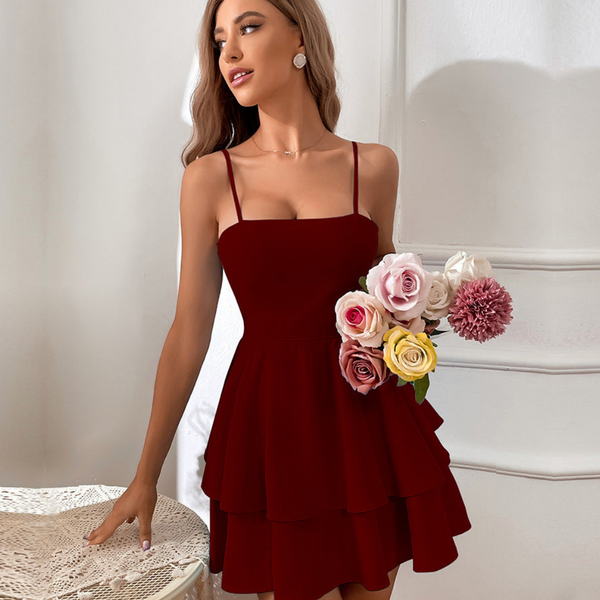 Vrouw in elegante bordeauxrode jurk met spaghettibandjes, houdt een boeket kleurrijke bloemen vast. Perfecte outfit voor feestelijke gelegenheden.
