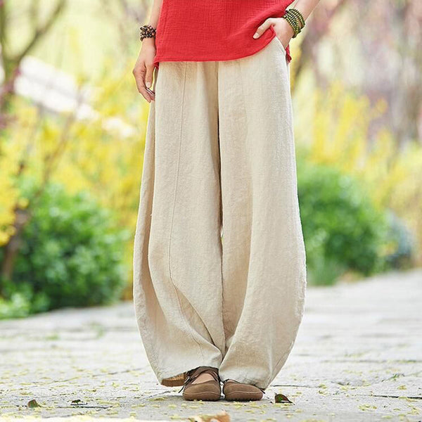 Vrouw draagt wijde linnen broek in beige, gecombineerd met rode top. Casual lente- of zomeroutfit, comfortabele en modieuze kledingstijl.