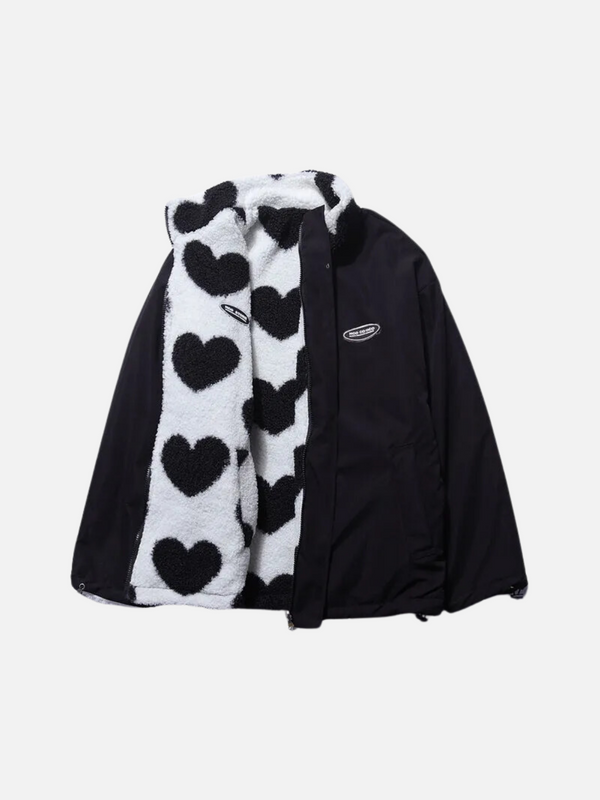 Zwarte jas met witte sjaal, versierd met zwarte hartjes. Trendy wintermode, warme kleding, stijlvolle jas en sjaal combinatie.