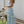 Vrouw in lange, blauwe bloemenjurk poseert buiten naast tafel met rozen. Zomerse mode, elegante dameskleding, tuinfeest outfit.