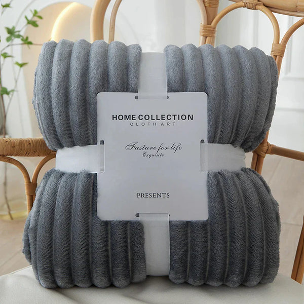Grijze fleece deken op rotan stoel, Home Collection, zacht en warm, ideaal voor woonkamer of slaapkamer, luxe interieuraccessoire.