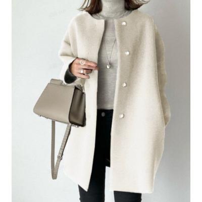 Dame in elegante witte mantel met parelknopen, grijze coltrui en stijlvolle beige handtas. Modieuze winteroutfit, minimalistisch design.
