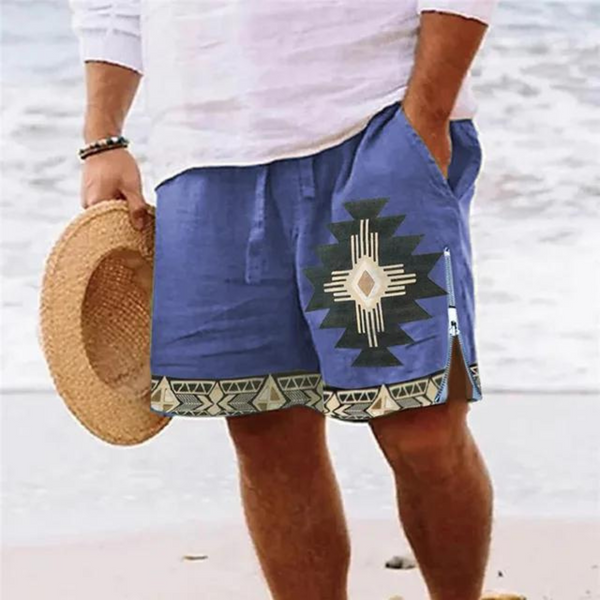 Man in blauwe zwembroek met Azteeks patroon en strohoed op strand. Zomerse strandmode, heren zwemkleding, casual strandoutfit.