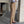 Man in beige pantalon en bruine loafers, gekruiste armen, gestreept overhemd, moderne betonnen omgeving. Stijlvolle herenmode, zakelijke casual look.