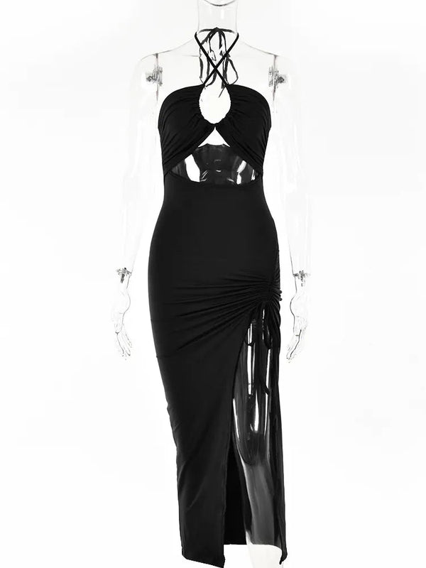 Zwarte midi-jurk met halternek en uitsnijdingen, ruches en hoge split. Perfect voor avondkleding en feestjes. Elegante en trendy damesmode.