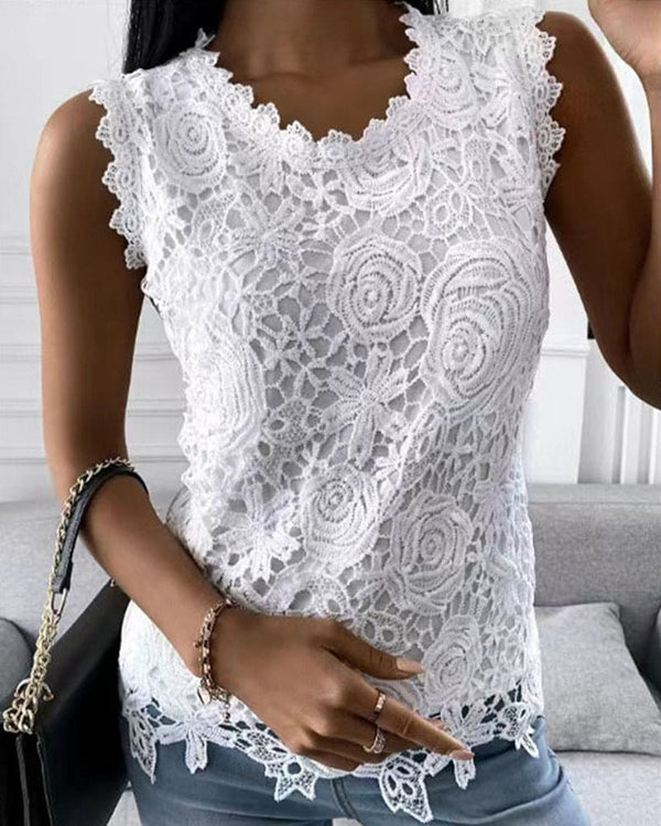Vrouw draagt witte kanten top met bloemenpatroon, gecombineerd met blauwe jeans en zwarte handtas. Modieuze zomerse outfit, elegant en stijlvol.