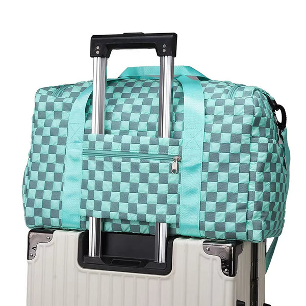 Turquoise geruite reistas op witte rolkoffer, lichtgewicht en duurzaam, ideaal voor reizen. Handbagage met ritsvak en verstelbare schouderriem.