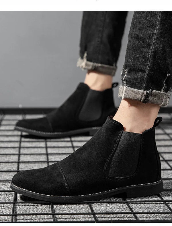 Zwarte suède Chelsea boots voor heren, gedragen met opgerolde jeans. Stijlvolle enkellaarzen, perfect voor casual en formele gelegenheden.