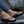 Vrouwelijke voeten in zwarte platform teenslippers met strass, gedragen met jeans. Modieuze zomerschoenen, casual stijl, buitenomgeving.