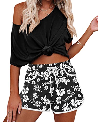 Zwarte off-shoulder top met knoop, gecombineerd met zwart-witte bloemenprint shorts. Zomerse dameskleding, casual en trendy outfit.