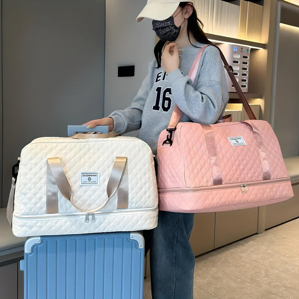 Vrouw met grijze trui en pet draagt roze gewatteerde reistas, naast beige reistas op blauwe koffer. Reistassen, bagage, modeaccessoires.