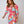 Vrouw in kleurrijke gestreepte jurk met roze, blauwe en oranje tinten, modieuze uitstraling, trendy damesmode, stijlvolle kleding.