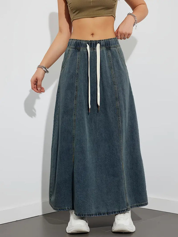 Vrouw in denim maxi-rok met elastische tailleband en witte sneakers, casual mode, trendy dameskleding, comfortabele outfit voor dagelijks gebruik.