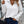 Vrouw in witte geribbelde trui met halve rits, blauwe jeans en zwarte leren schoudertas. Modieuze casual outfit voor dames.