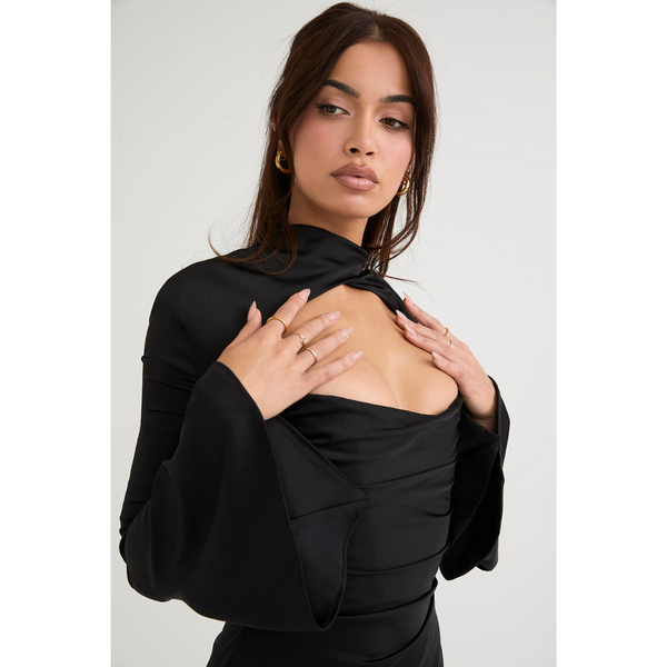 Vrouw in elegante zwarte jurk met wijde mouwen en open halslijn, poseert voor minimalistische achtergrond. Modieuze dameskleding, stijlvolle outfit.