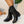 Zwarte leren dameslaarzen met lage hak op witte kiezelstenen, stijlvolle herfstmode, comfortabele enkellaarzen, trendy schoenen voor dagelijks gebruik.