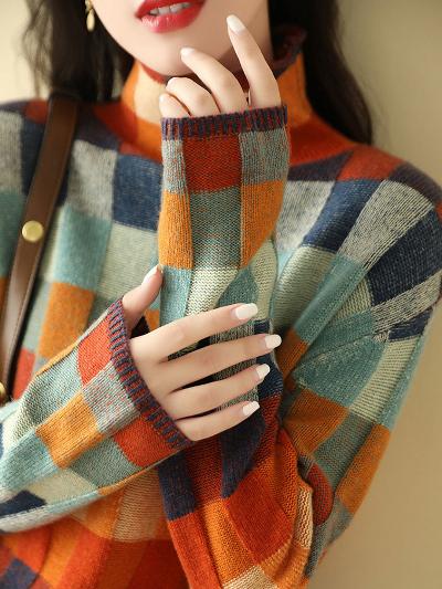 Vrouw in kleurrijke geruite trui met lange mouwen, oranje en blauwe tinten, modieuze herfstkleding, stijlvolle damesmode, close-up.