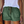 Vrouw draagt groene katoenen shorts met ruches en zakken, gecombineerd met een witte top. Trendy zomermode, casual dameskleding, comfortabele stijl.