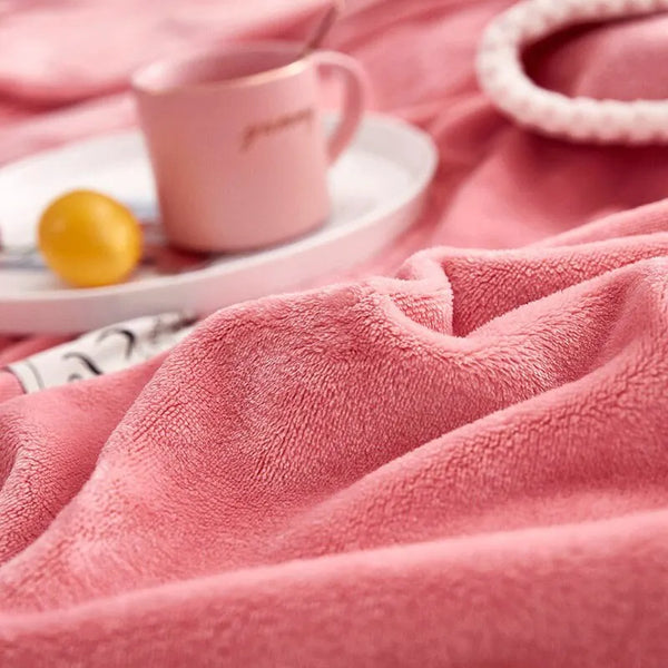 Roze fleece deken op bed met kopje koffie en citroen op een dienblad. Zachte textuur, warme uitstraling, perfect voor gezellige winteravonden.