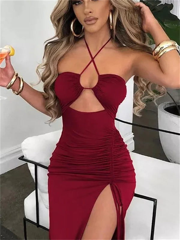 Vrouw in elegante rode jurk met halternek en hoge split, zittend op een bank. Perfect voor avondkleding, mode en stijl.