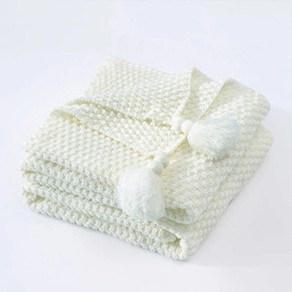 Gevouwen witte gebreide deken met kwastjes, zachte textuur, perfect voor interieurdecoratie, woonkamer, slaapkamer, Scandinavisch design.