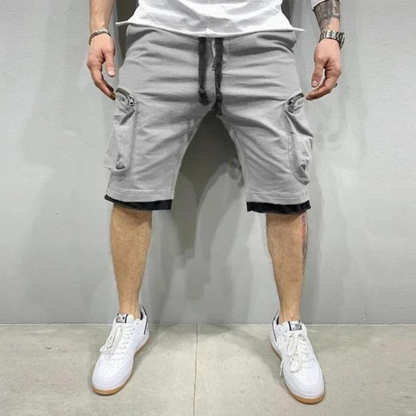 Grijze cargoshorts voor heren met zakken, casual streetwear stijl, gecombineerd met witte sneakers en een wit T-shirt, trendy zomeroutfit.