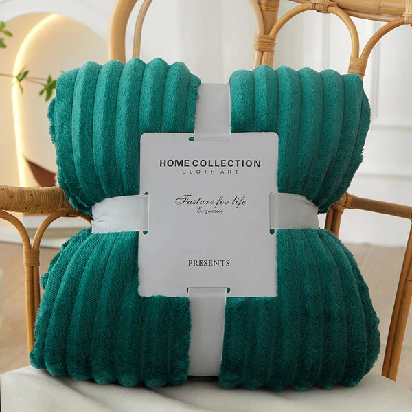 Groene fleece deken, geribbeld design, verpakt met wit label "Home Collection Clothart", op houten stoel. Perfect voor interieurdecoratie en comfort.