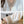 Witte blouse met V-hals en beige borduursel, gecombineerd met een horloge en grijze broek. Elegante damesmode, stijlvolle blouse details.