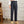 Man in stijlvolle donkerblauwe pantalon met hoge taille en beige loafers, staand op houten vloer. Elegante herenmode, klassieke broekstijl.