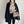 Vrouw in stijlvolle herfstoutfit met zwarte jas, grijze trui en beige handtas. Modieuze dameskleding, herfstmode, casual chic look.