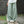 Vrouw in wijde, lichtgroene linnen broek en witte top, staand op stenen pad. Comfortabele, casual mode voor dames, lente/zomer outfit.