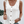Vrouw draagt witte, mouwloze blouse met knopen en broderie details, gecombineerd met denim shorts. Zomermode, casual dameskleding.