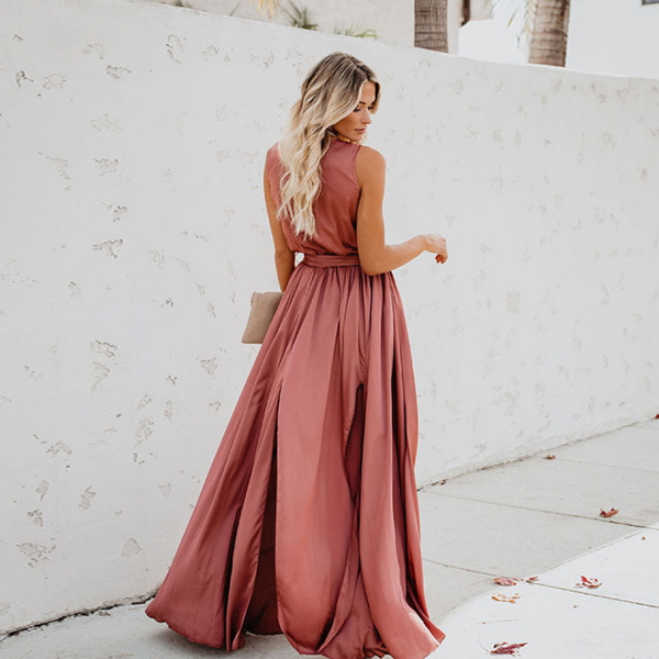 Vrouw in elegante roze avondjurk met lange rok, poseert tegen witte muur. Perfect voor bruiloft, gala of feest. Stijlvolle modefotografie.