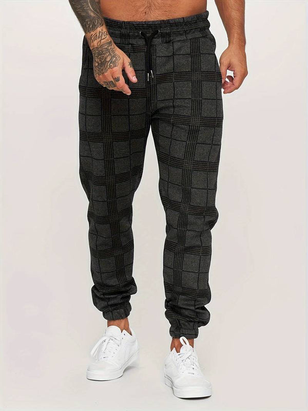 Grijze geruite joggingbroek voor heren, gedragen met witte sneakers. Comfortabele streetwear-stijl, ideaal voor casual en sportieve looks.